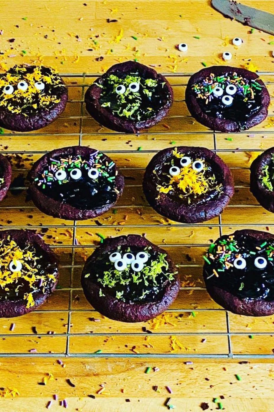 Monster cookie cups filled with jam and marmalades, topped with icing eyes, sprinkles and orange and lime zest