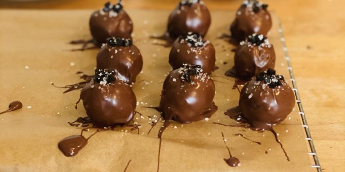 9 devilishly dark chocolate truffles on parchment paper, topped with liquorice pieces and sea salt