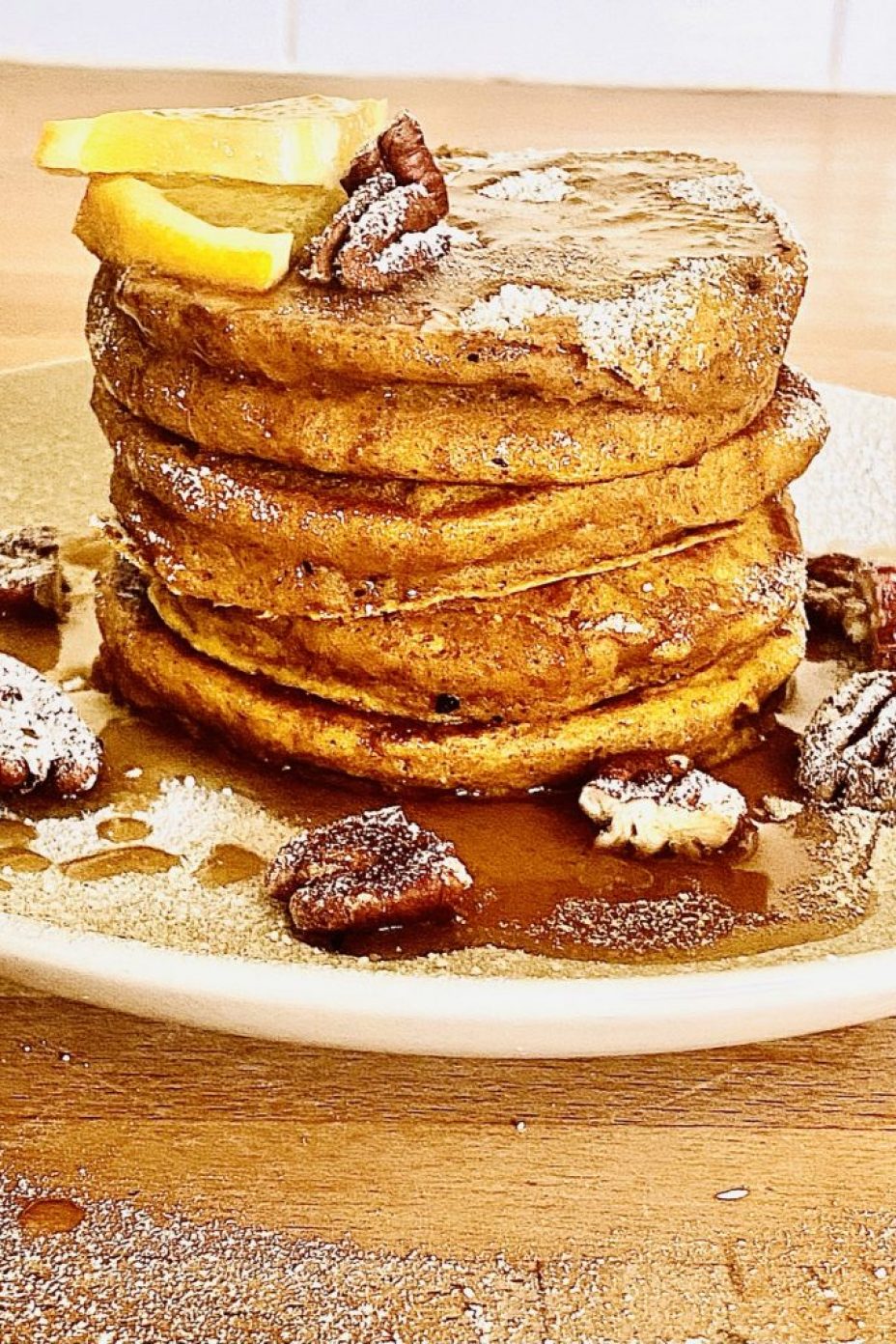 Stack of pumpkin spiced pancakes with maple orange syrup and toasted pecan nuts