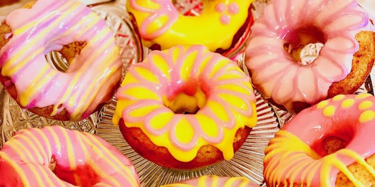 Baked doughnuts topped with coloured icing displayed on a cake stand