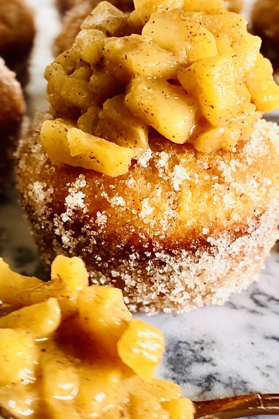 Apple pie muffins with a big pile of stewed apples on top of the cinnamon sugar coated vanilla muffins