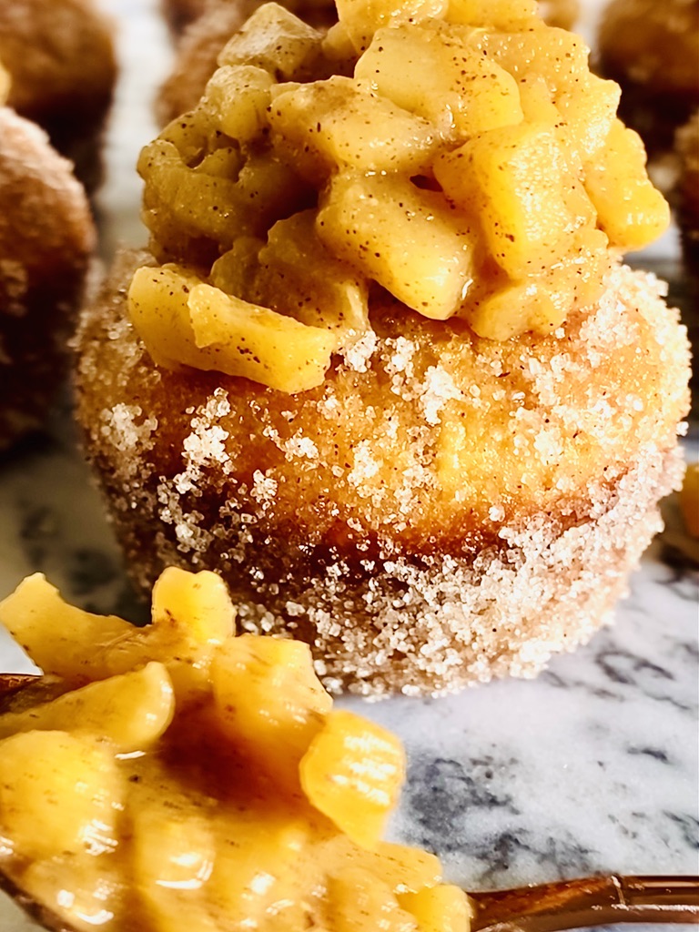 Apple pie muffins with a big pile of stewed apples on top of the cinnamon sugar coated vanilla muffins